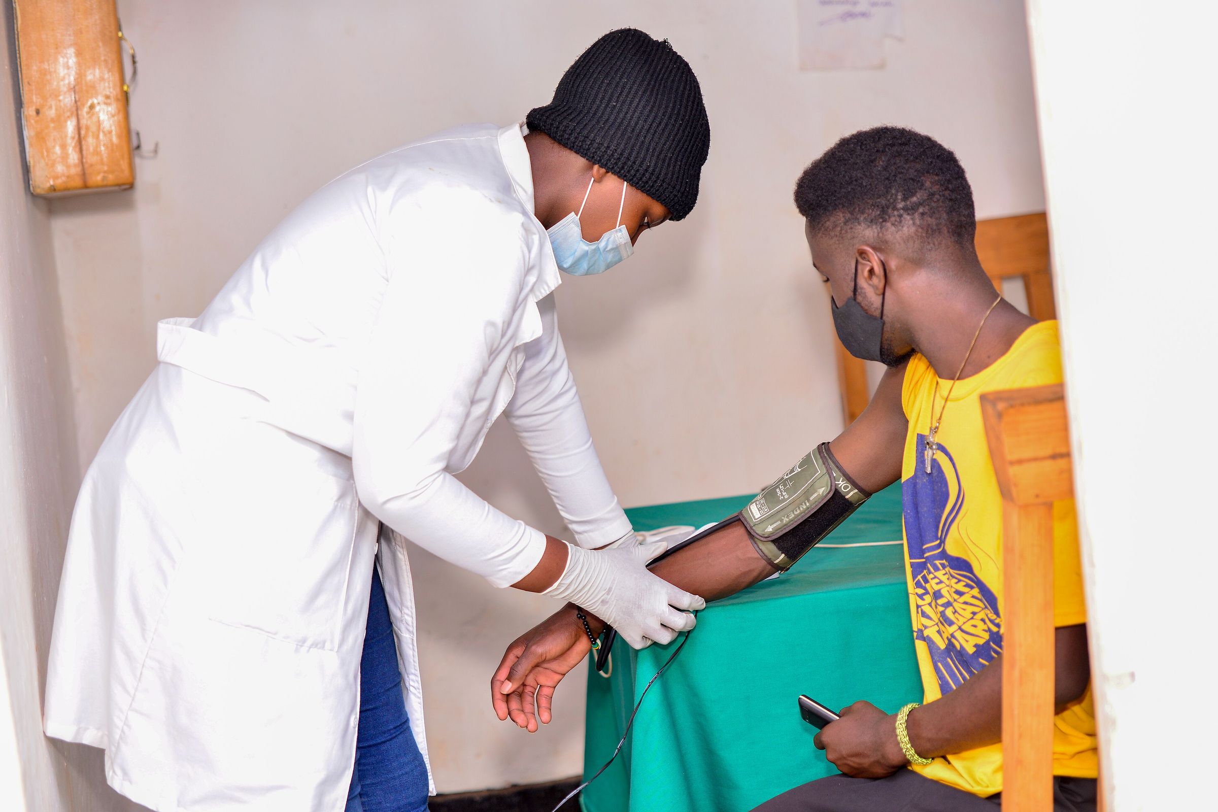 A health worker checks a young man’s blood pressure during a community screening in Rwanda